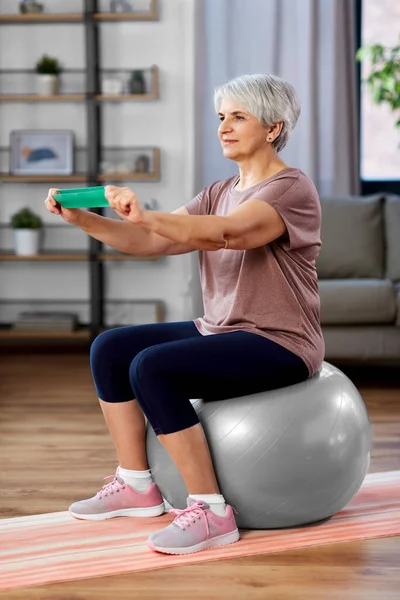 Mujer mayor haciendo ejercicio con banda elástica en casa — Foto de Stock