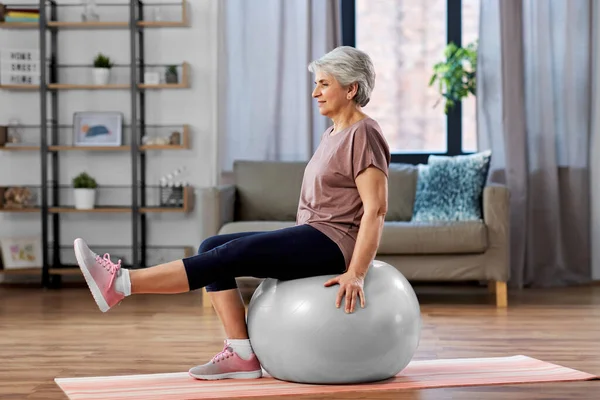 Mujer mayor de entrenamiento con pelota de ejercicio en casa — Foto de Stock