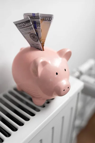 Spaarvarken bank met geld op radiator thuis — Stockfoto