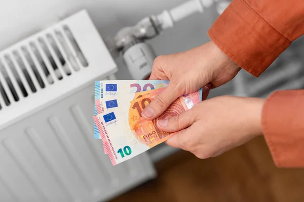 Close-up van handen met geld op radiator thuis — Stockfoto