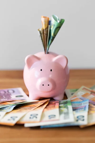 Close-up de banco porquinho com dinheiro na mesa de madeira — Fotografia de Stock