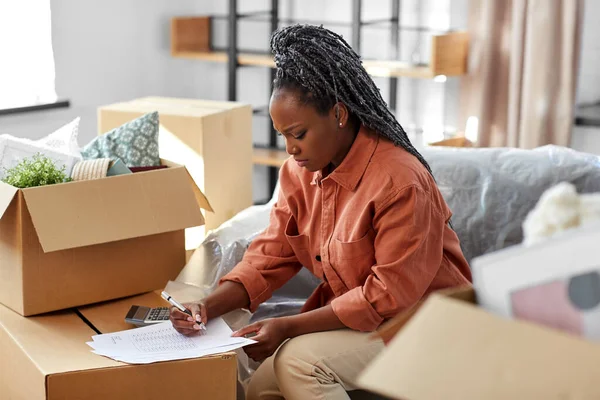 Vrouw met rekeningen en rekenmachine verhuizen naar nieuw huis — Stockfoto