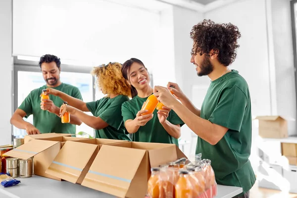 Heureux bénévoles emballant de la nourriture dans des boîtes de dons — Photo