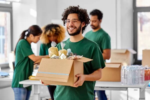 Voluntarios felices empacando comida en cajas de donaciones —  Fotos de Stock