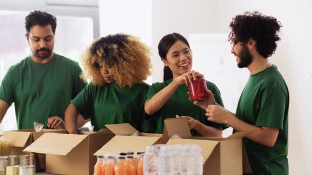 Voluntários felizes embalando alimentos em caixas de doação — Vídeo de Stock