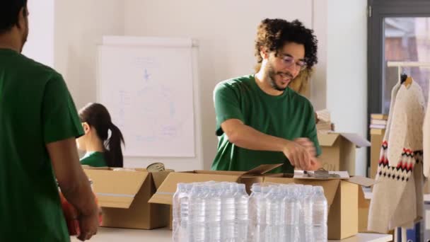 Grupo de voluntários embalando alimentos em caixas de doação — Vídeo de Stock