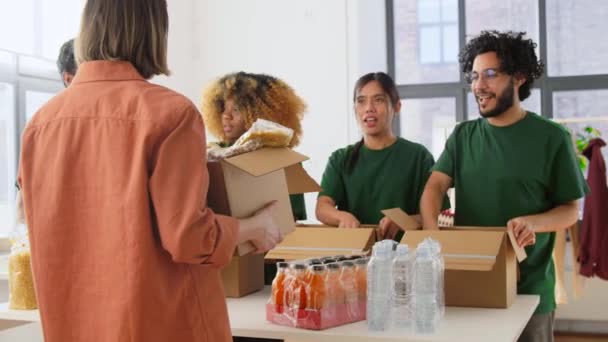 Voluntários felizes embalando alimentos em caixas de doação — Vídeo de Stock