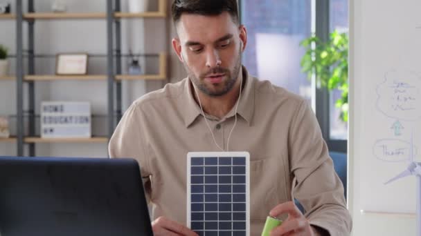 Мужчина учитель с ноутбуком и солнечной батареей дома — стоковое видео