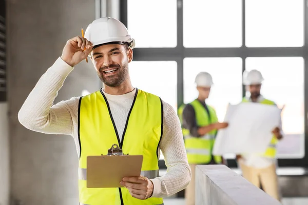 Arquiteto masculino no capacete com prancheta no escritório — Fotografia de Stock