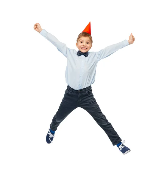 Garotinho sorridente em chapéu de festa de aniversário pulando — Fotografia de Stock