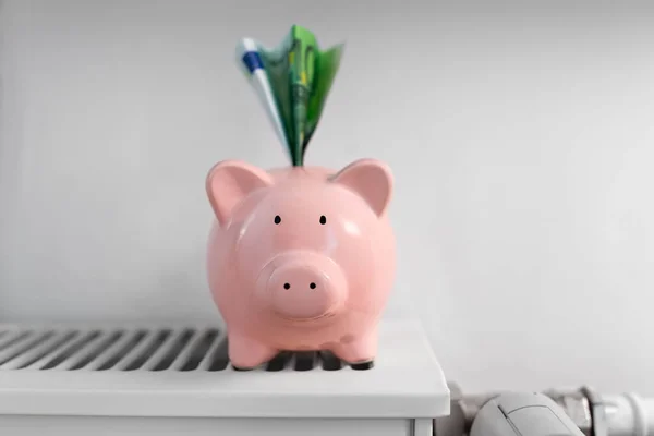 Banco porquinho com dinheiro no radiador em casa — Fotografia de Stock