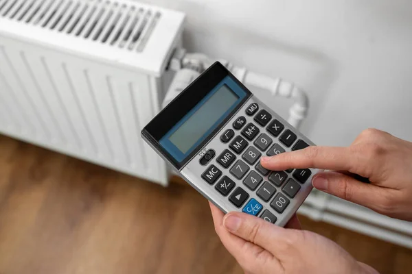 Close-up van de hand met rekenmachine en home radiator — Stockfoto