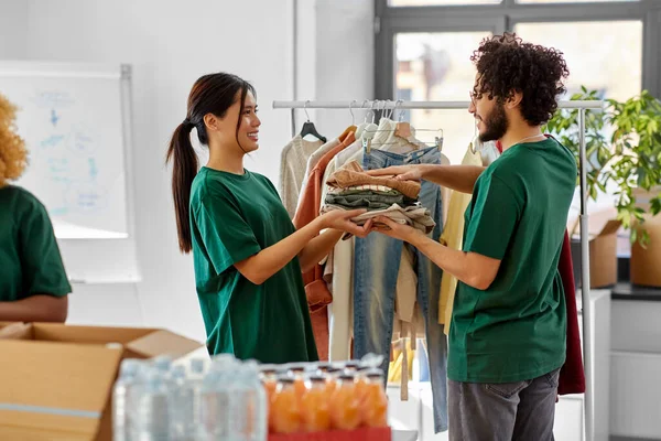 Voluntários felizes embalando alimentos e roupas em caixas — Fotografia de Stock