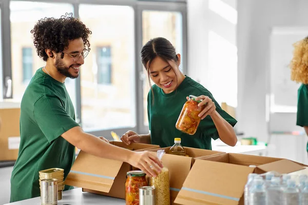 happy volunteers packing food in donation boxes