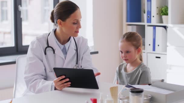 Doktor klinikteki küçük kıza tableti gösteriyor. — Stok video