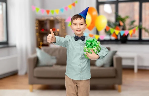 Menino feliz com presente de aniversário mostrando polegares para cima — Fotografia de Stock