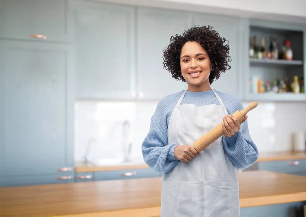 Mujer sonriente en delantal con rodillo en la cocina — Foto de Stock