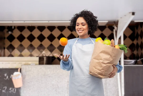 Mulher com alimentos em saco de papel sobre caminhão de alimentos — Fotografia de Stock