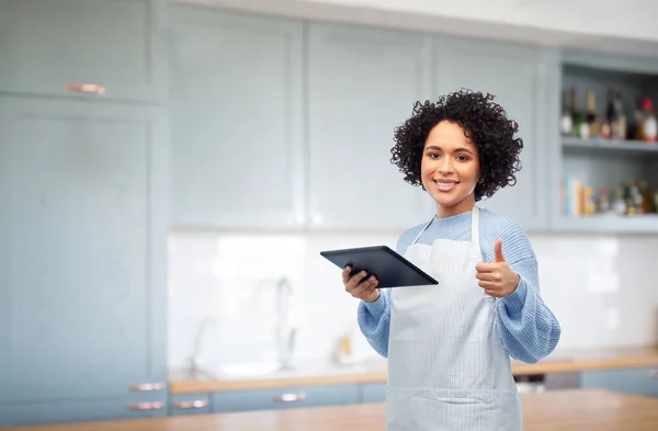 Donna con tablet pc mostrando pollici in cucina — Foto Stock