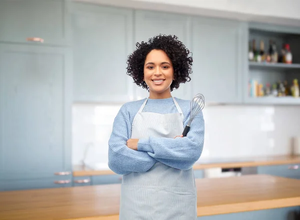Uśmiechnięta kobieta w fartuchu z trzepaczką w kuchni — Zdjęcie stockowe