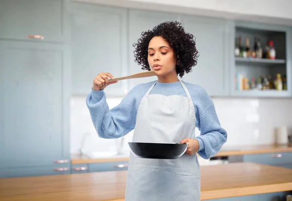 Mulher com frigideira degustação de alimentos na cozinha — Fotografia de Stock