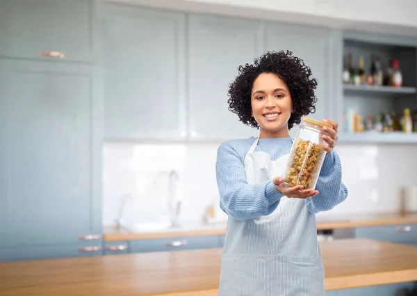 Donna sorridente che tiene il vaso con la pasta in cucina — Foto Stock