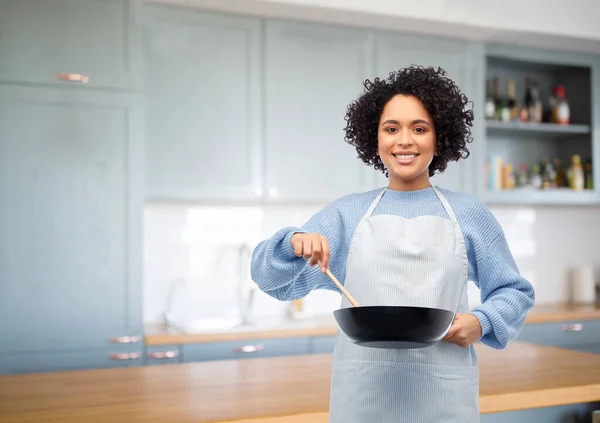 Glad kvinna matlagning mat i stekpanna i köket — Stockfoto