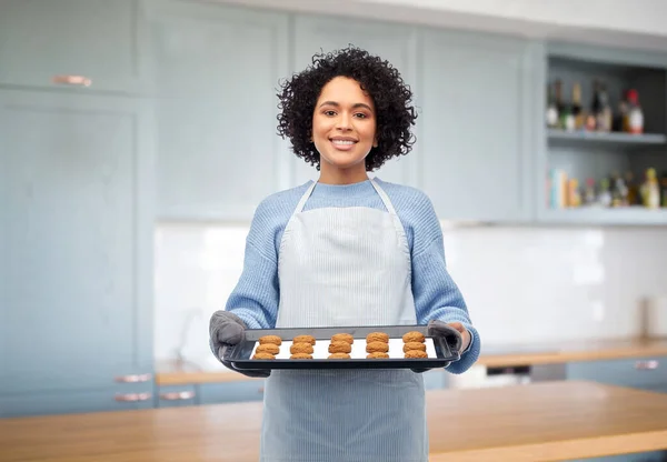 Mujer sosteniendo bandeja para hornear con galletas en la cocina — Foto de Stock