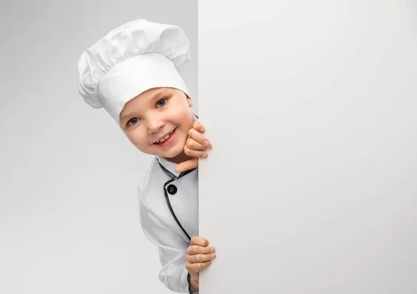 Menina feliz em chefs toque com placa branca — Fotografia de Stock