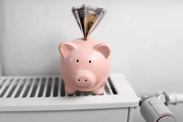 Sparschwein mit Geld auf Heizkörper zu Hause — Stockfoto