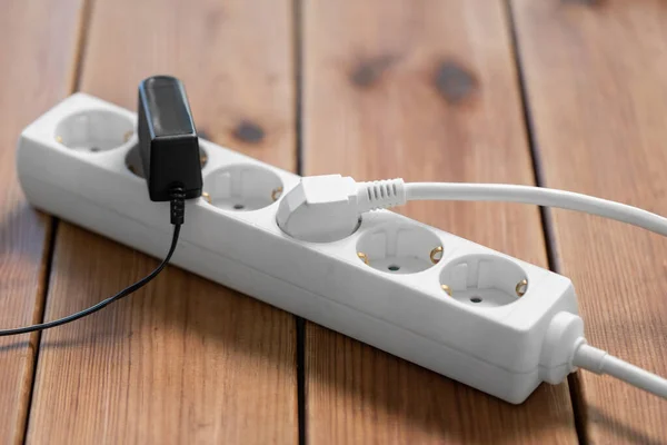 Close up of socket with plugs and charger on floor — Stock Photo, Image