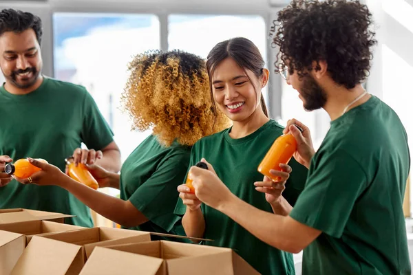 Voluntários felizes embalando alimentos em caixas de doação — Fotografia de Stock