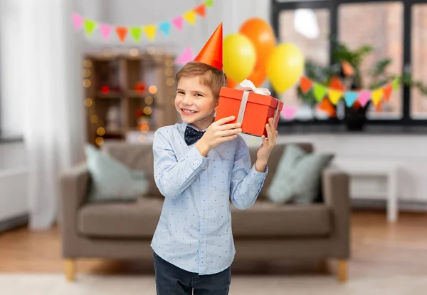 Niño sonriente en sombrero de fiesta con regalo de cumpleaños — Foto de Stock