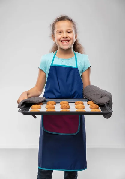 Lány kötényben tartja sütő tálca sütemények — Stock Fotó