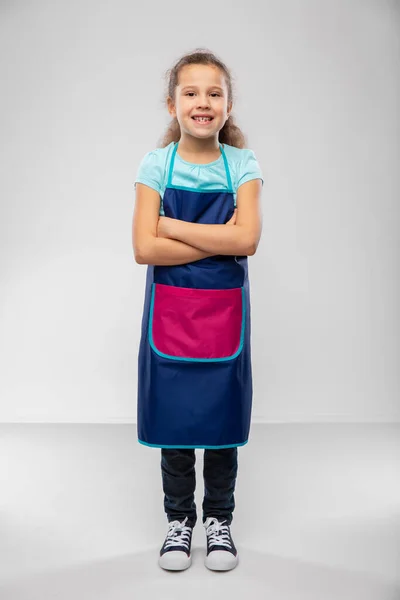 Glimlachend klein meisje in schort met gekruiste armen — Stockfoto