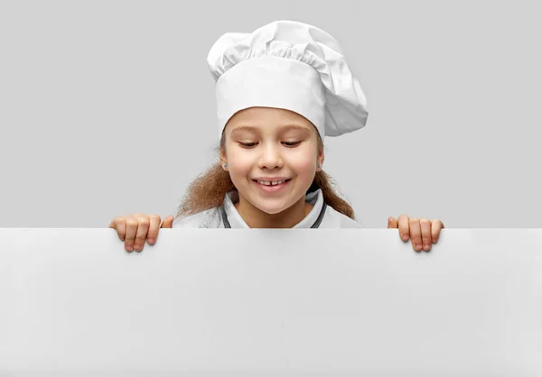 Menina feliz em chefs toque com placa branca — Fotografia de Stock