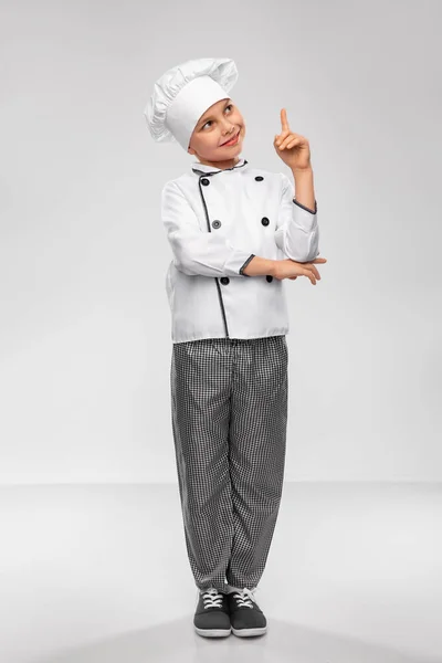 Маленький хлопчик у кухарях вказує пальцем вгору — стокове фото
