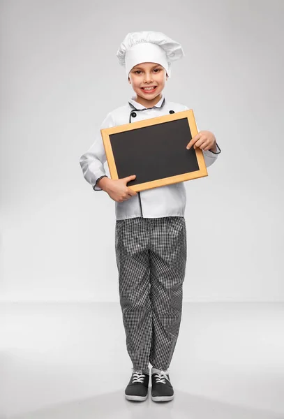 Happy little boy in chefs toque with chalkboard — Stock Photo, Image