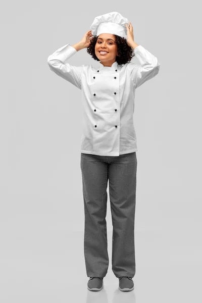 Glimlachende vrouwelijke chef-kok in witte toque en jas — Stockfoto