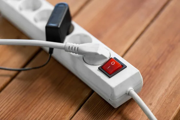 Close up of socket with plugs and charger on floor — Stock Photo, Image