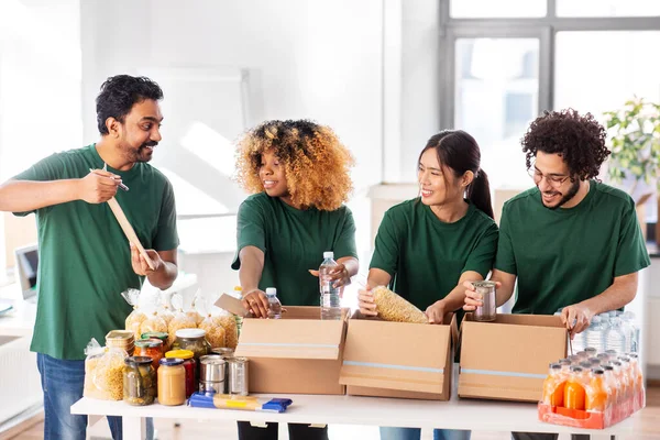 헌금 함에 식품을 포장하는 행복 한 자원 봉사자들 — 스톡 사진