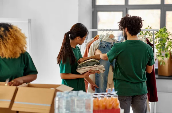 Voluntários felizes embalando alimentos e roupas em caixas — Fotografia de Stock