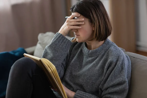 Weinende Frau mit Tagebuch sitzt zu Hause auf Sofa — Stockfoto