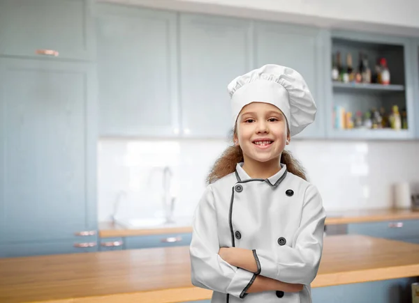 Smiling little girl in chefs toque in kitchen — ストック写真