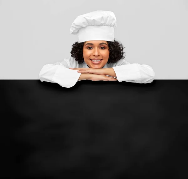 Smiling female chef with black chalkboard — Stock Photo, Image