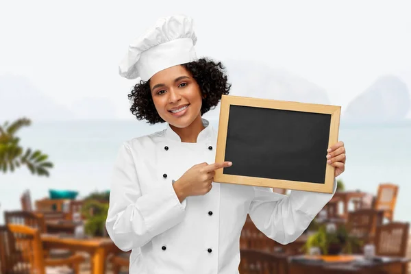 Glimlachende vrouwelijke chef met zwart schoolbord — Stockfoto