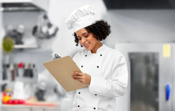 Chef feminino sorridente com prancheta na cozinha — Fotografia de Stock