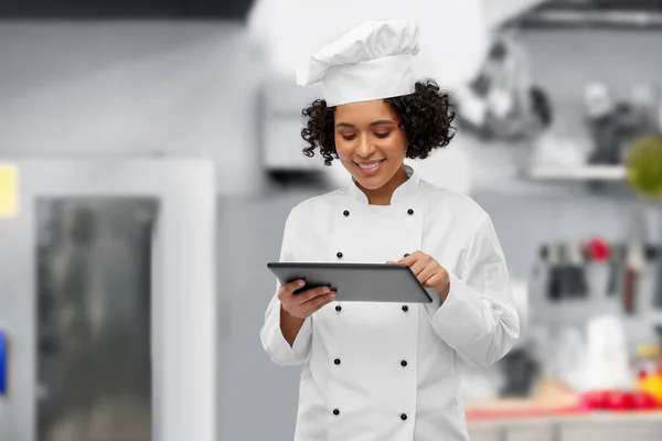 Sorridente chef feminino com tablet pc na cozinha — Fotografia de Stock