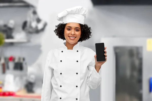 Chef mujer sonriente mostrando teléfono inteligente en la cocina —  Fotos de Stock