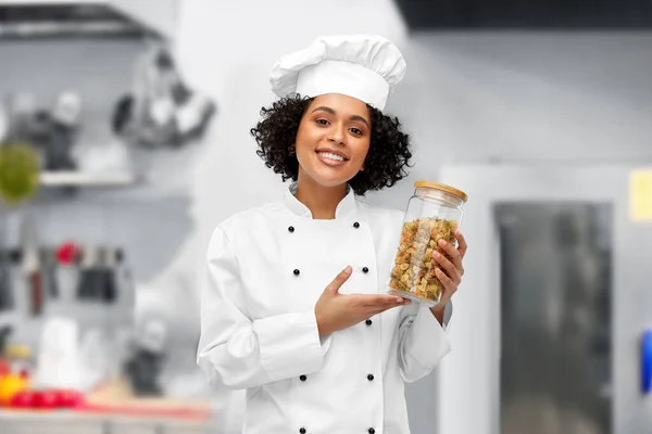Female chef holding jar with pasta in kitchen — Stok fotoğraf